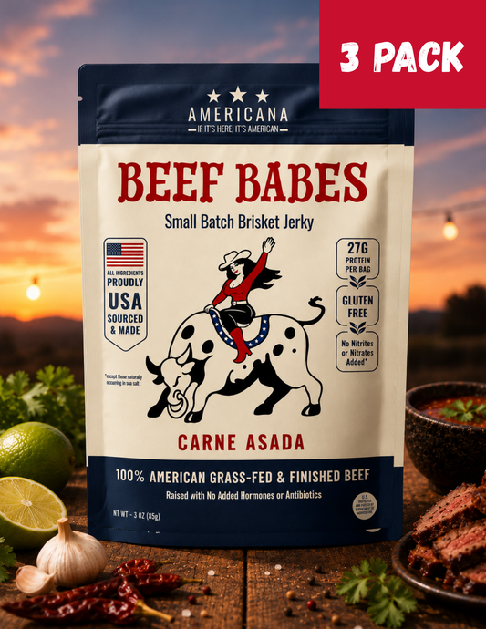 A 3-pack bag of Americana Beef Babes Carne Asada small batch brisket jerky, displayed on a rustic wooden table with raw ingredients (lime, garlic, chili peppers) and cooked meat slices, set against a warm sunset background with a red '3 PACK' banner overlay.