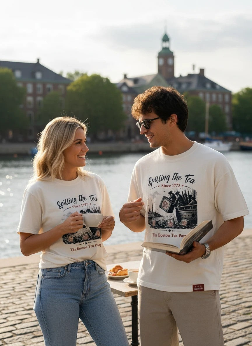 Americana couple wearing off-white cotton crewneck t-shirts with vintage Boston Tea Party graphic by a waterfront.